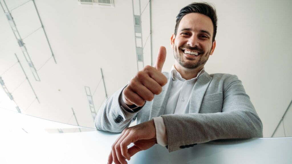 Happy business man shows thumb up sign gesture