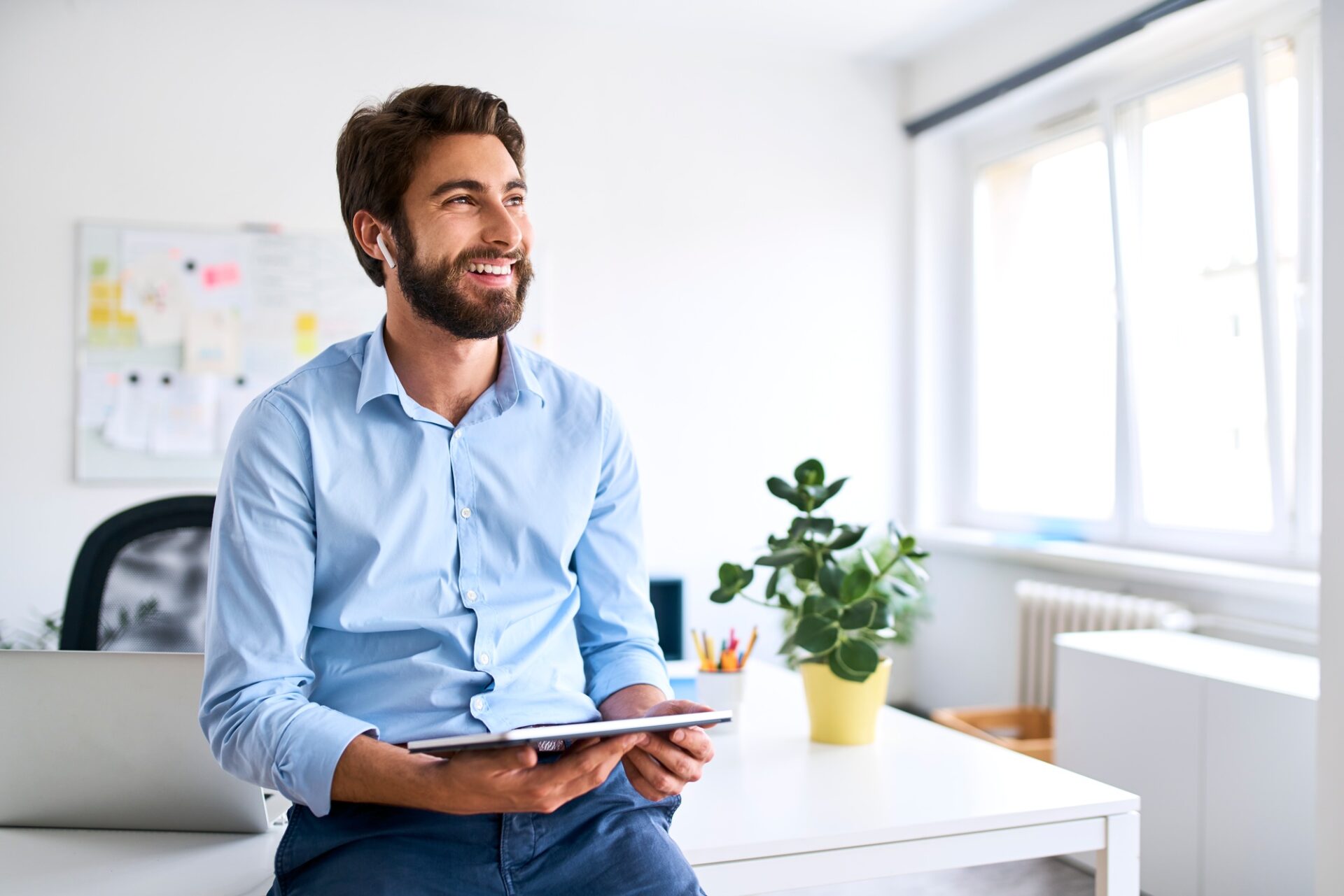 Smiling businessman with headphones using a digital tablet in his office Smiling businessman with headphones using a digital tablet in his office