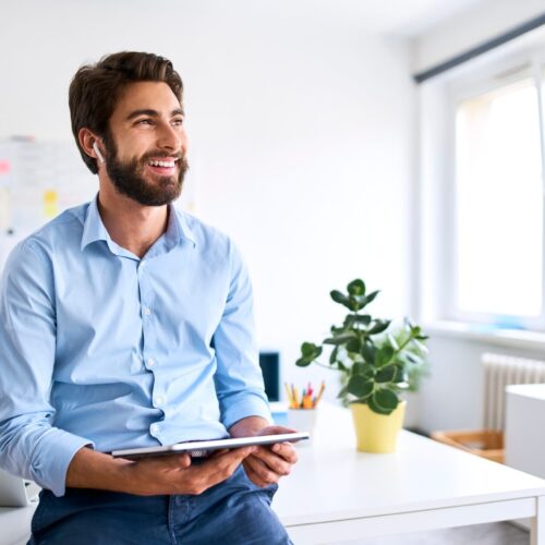 Smiling businessman with headphones using a digital tablet in his office Smiling businessman with headphones using a digital tablet in his office